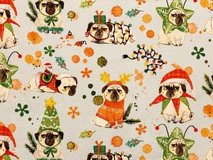 Light blue fabric with pattern of grumpy looking pug dogs wearing Christmas outfits