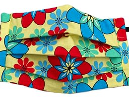 Yellow fabric with red, blue and turquoise flower shapes that resemble atomic symbols mask closeup