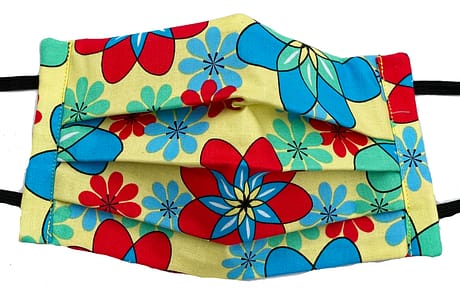 Yellow fabric with red, blue and turquoise flower shapes that resemble atomic symbols mask closeup