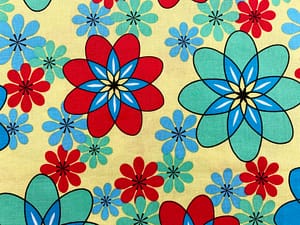 Yellow fabric with red, blue and turquoise flower shapes that resemble atomic symbols