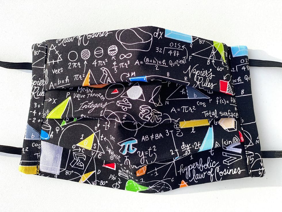 Equations Mask Closeup | closeup of black fabric with white handwritten font of various equations and colourful geometric shapes