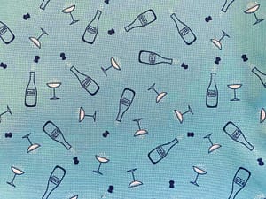 Blue fabric with pattern of champagne bottles and glasses outlined in black